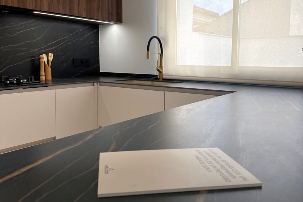 Cocina moderna con isla en mármol negro y muebles en beige y madera