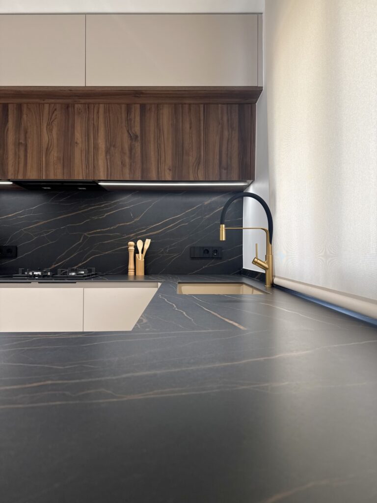 Encimera de cocina en mármol negro con vetas doradas y tabla de cortar blanca